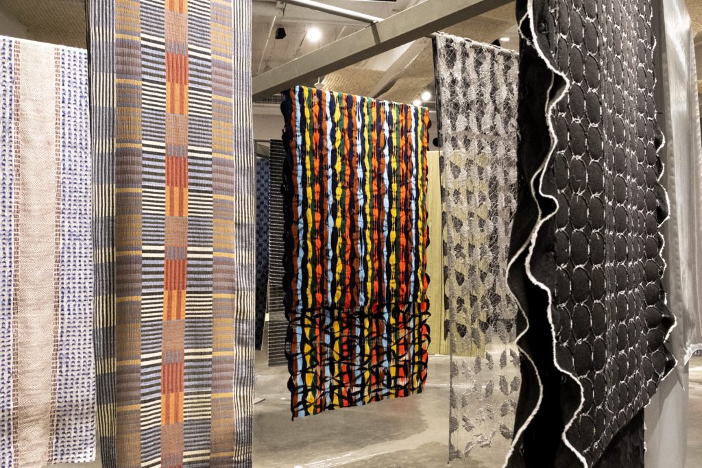 Foto de ambiente com grandes painéis de tecidos sustentáveis pendurados.